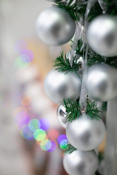 Silver baubles on spruce twigs and decorated fireplace in background.
