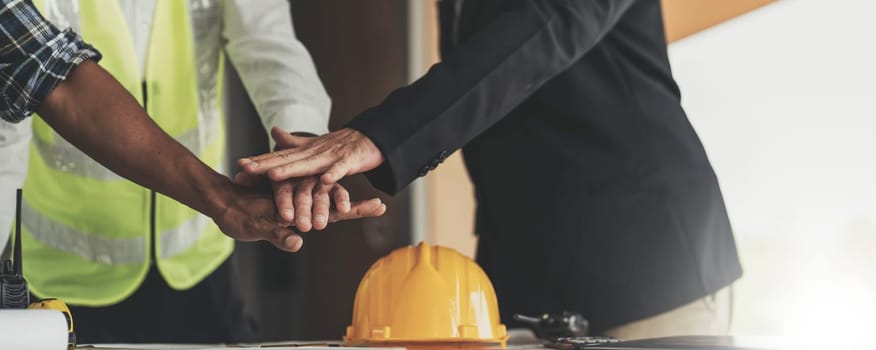 Civil engineer teams meeting working together wear worker helmets hardhat on construction site in modern city. Foreman industry project manager engineer teamwork. Asian industry professional team..