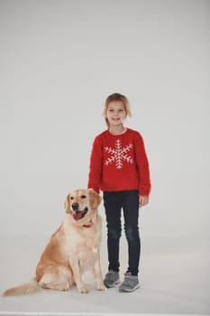 Little girl is with cute Golden retriever in the studio against white background.