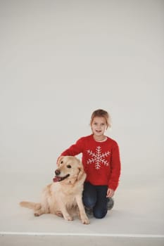 Little girl is with cute Golden retriever in the studio against white background.