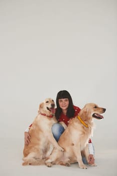 Woman is with her two Golden retrievers in the studio against white background.