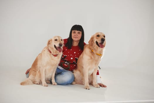 Woman is with her two Golden retrievers in the studio against white background.