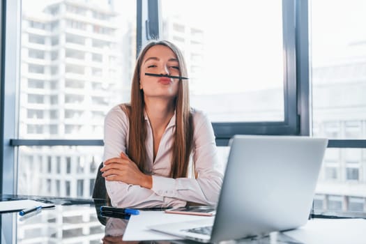 Have fun at break. Young woman in white formal clothes is indoors in the modern office.