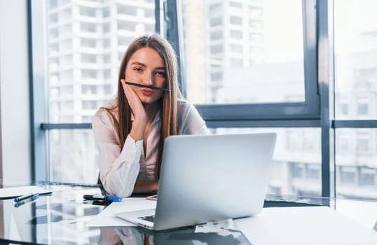 Have fun at break. Young woman in white formal clothes is indoors in the modern office.
