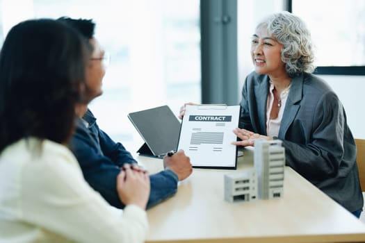 Guarantee Insurance Sign a contract, couple a smiling couple is signing a contract to invest in real estate with the Mortgage officer with the bank.