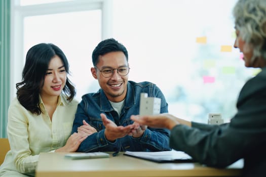 Guarantee Insurance Sign a contract, couple a smiling couple is signing a contract to invest in real estate with the Mortgage officer with the bank.