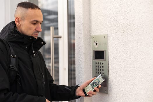 Cut in picture hand of a man turning on the intercom with smartphone outdoor close up