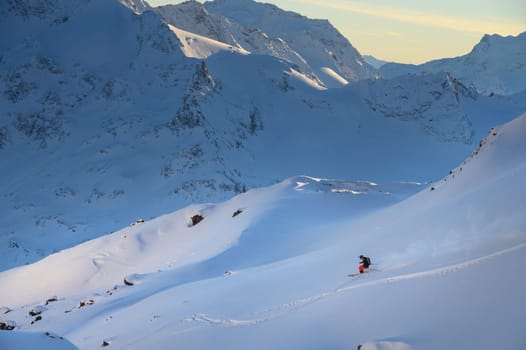 Freerider skier down the powder snow at sunset, italian alps. Skier at ski resort off-piste, colorful winter sunset.