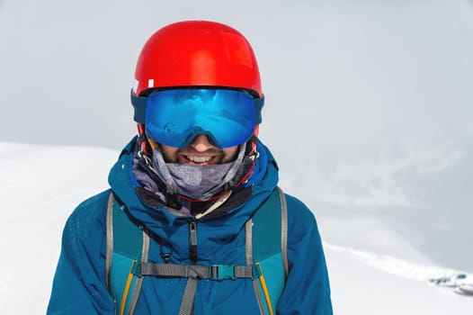 Cheerful skier looking at camera before starting to skiing. Happy man enjoying holiday in winter season. Smiling mountaineer skier in winterwear with ski equipment and copy space.