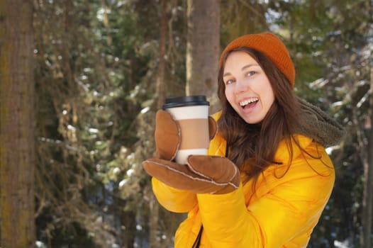 people, hot drinks and leisure concept. happy woman drinking takeaway coffee in winter outdoors showing her glass to camera.