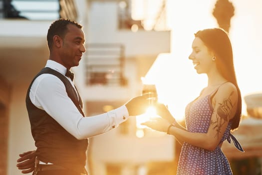 Order for woman. Black waiter in formal clothes is at his work outdoors at sunny daytime.
