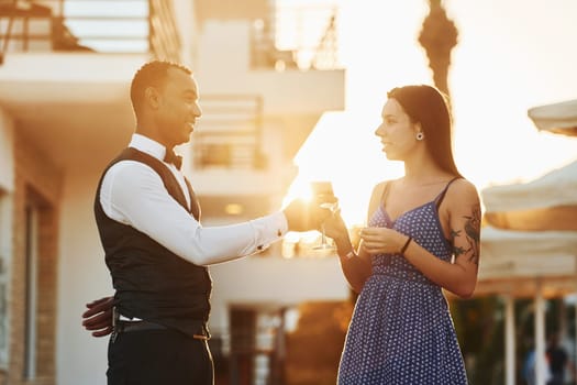 Order for woman. Black waiter in formal clothes is at his work outdoors at sunny daytime.