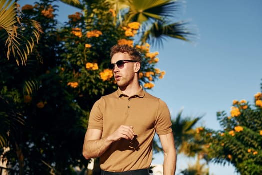 In sunglasses. Young man is outdoors at sunny daytime. Concept of vacation.