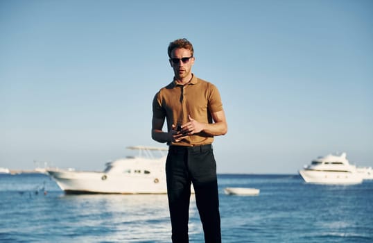 In sunglasses. Young man is outdoors at sunny daytime. Concept of vacation.