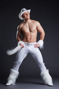 Full length portrait of muscular dancer in white cowboy costume