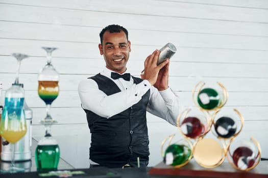 At the bar. Black waiter in formal clothes is at his work outdoors at sunny daytime.