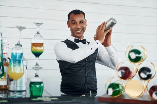 At the bar. Black waiter in formal clothes is at his work outdoors at sunny daytime.