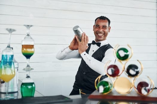 At the bar. Black waiter in formal clothes is at his work outdoors at sunny daytime.