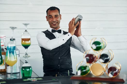 At the bar. Black waiter in formal clothes is at his work outdoors at sunny daytime.