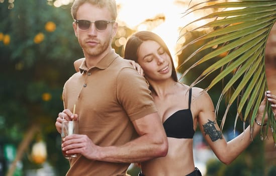 Man in sunglasses, woman in black bra. Happy young couple is together on their vacation. Outdoors at sunny daytime.