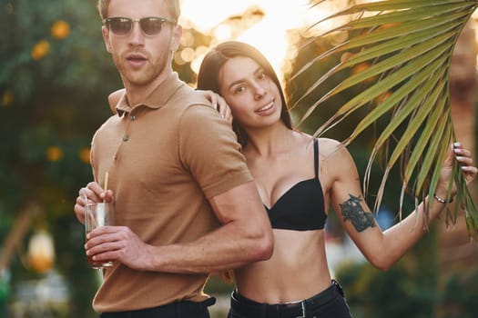 Man in sunglasses, woman in black bra. Happy young couple is together on their vacation. Outdoors at sunny daytime.