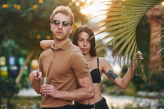 Man in sunglasses, woman in black bra. Happy young couple is together on their vacation. Outdoors at sunny daytime.