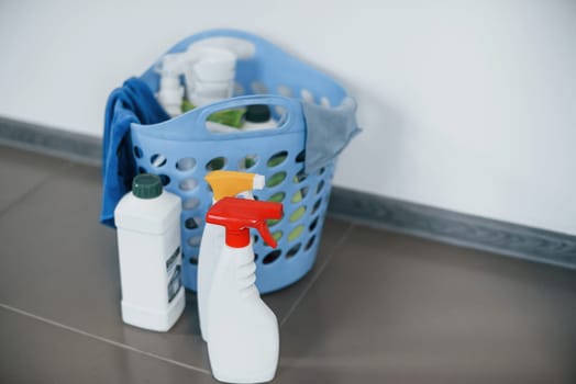 Close up view of bottles with detergent and basket indoors on the floor.