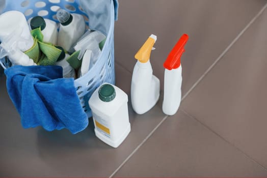 Close up view of bottles with detergent and basket indoors on the floor.