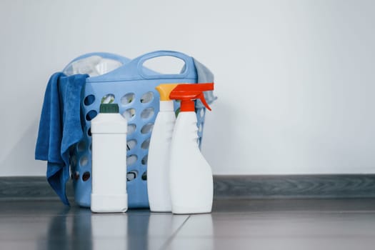 Close up view of bottles with detergent and basket indoors on the floor.