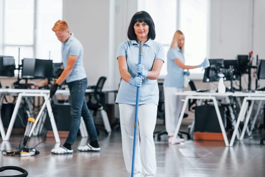 Group of workers clean modern office together at daytime.