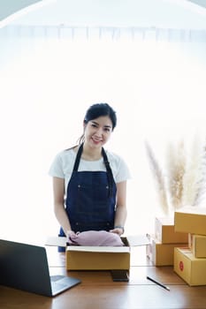 Starting small business entrepreneur of independent Asian woman smiling with cheerful success of online marketing package box items and SME delivery concept.