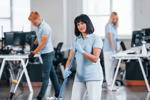 Group of workers clean modern office together at daytime.