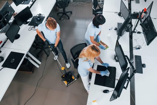 Top view. Group of workers clean modern office together at daytime.