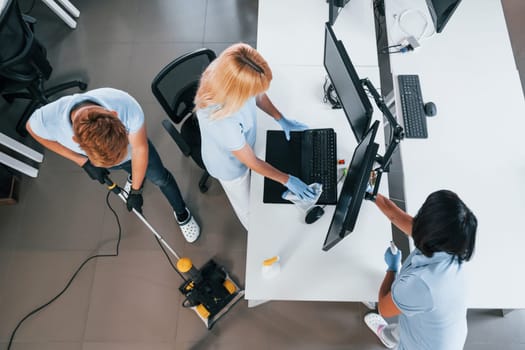 Top view. Group of workers clean modern office together at daytime.