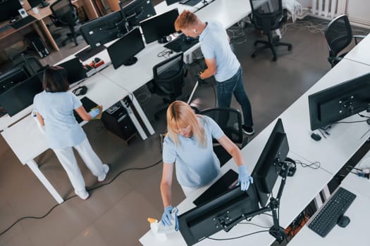 Top view. Group of workers clean modern office together at daytime.