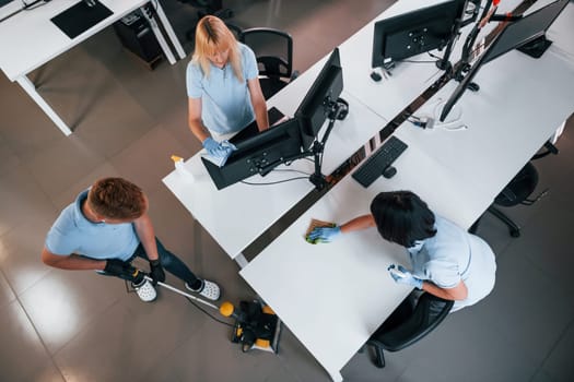 Top view. Group of workers clean modern office together at daytime.