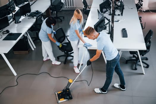 Concentrated at job. Group of workers clean modern office together at daytime.
