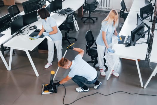 Concentrated at job. Group of workers clean modern office together at daytime.