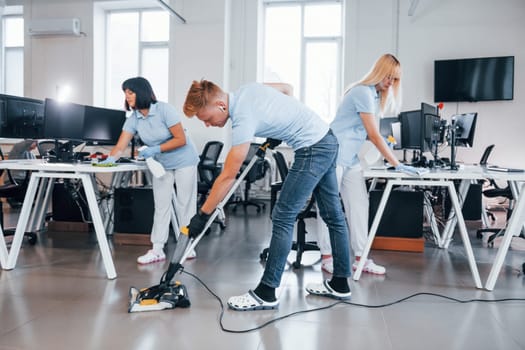 Concentrated at job. Group of workers clean modern office together at daytime.