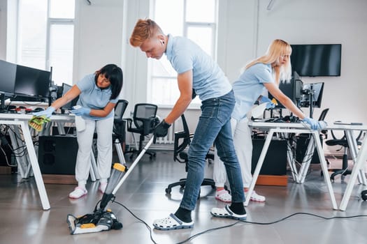Concentrated at job. Group of workers clean modern office together at daytime.