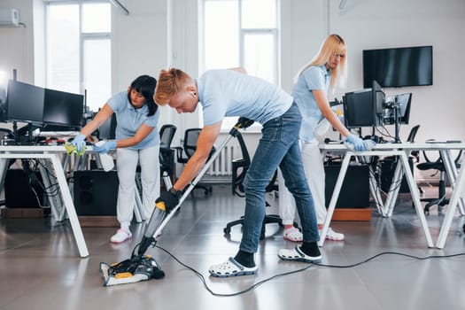 Concentrated at job. Group of workers clean modern office together at daytime.