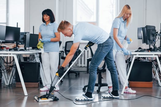 Concentrated at job. Group of workers clean modern office together at daytime.