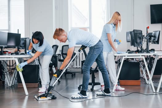 Concentrated at job. Group of workers clean modern office together at daytime.