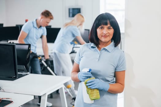 Group of workers clean modern office together at daytime.