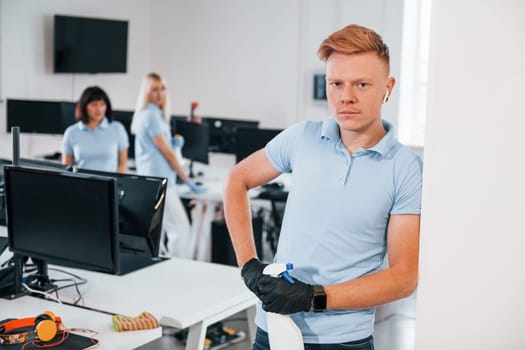 Group of workers clean modern office together at daytime.