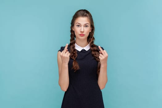Portrait of serious vulgar woman with braids showing middle finger, impolite gesture disrespects someone looks rude at camera, wearing black dress. woman Indoor studio shot isolated on blue background