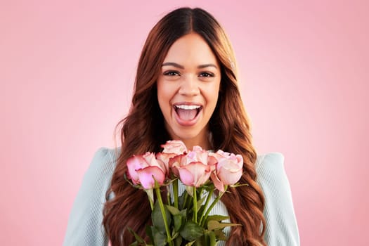 Happy, smile and woman with roses in a studio for valentines day, romance or anniversary. Happiness, excited and portrait of a female model from Mexico with a bouquet of flowers by a pink background