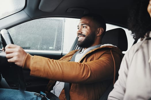 Man driving, rain and smile in city with car journey, winter travel and happiness for road trip. Guy driver, transportation and urban adventure with safety, vacation or holiday with excited face.