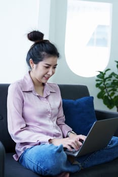 Portrait of a self-employed Asian woman using a computer at home.