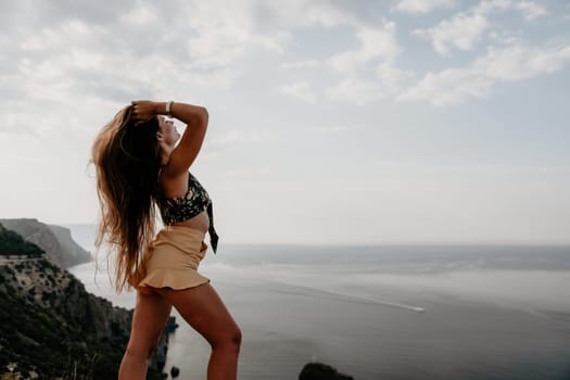 Woman travel sea. Happy tourist taking picture outdoors for memories. Woman traveler looks at the edge of the cliff on the sea bay of mountains, sharing travel adventure journey.